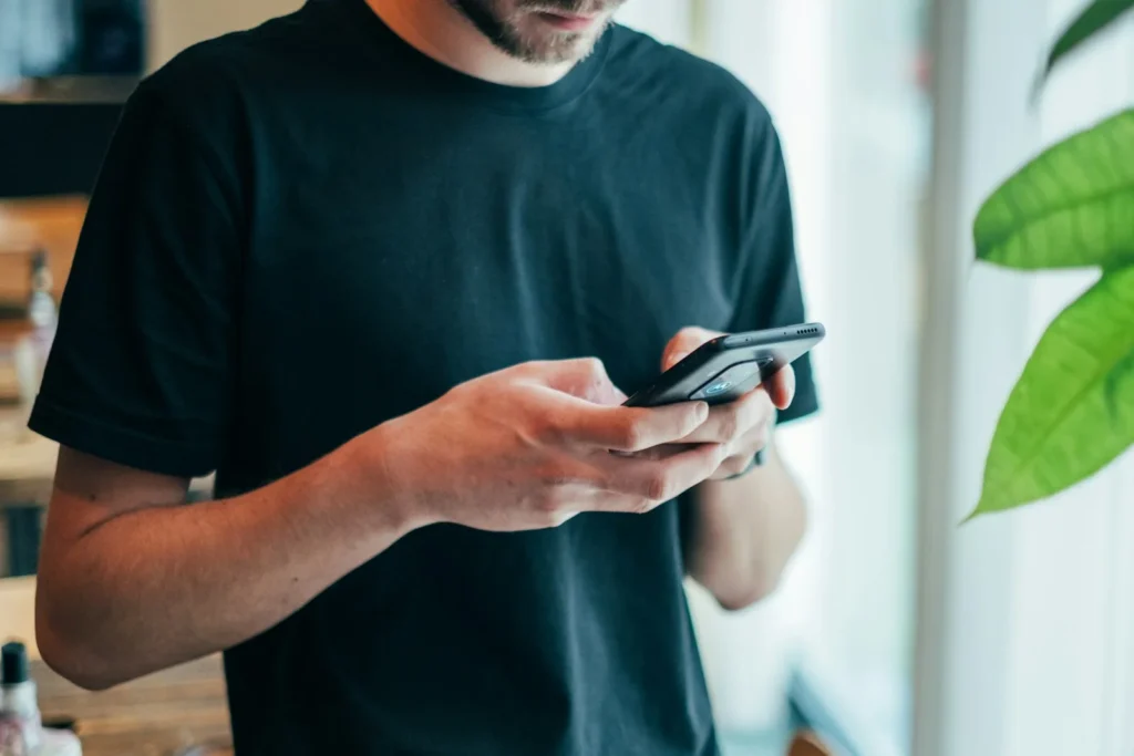 Shop owner checking WhatsApp messages on a smartphone, a use case for WhatsApp marketing software