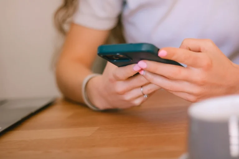 Close-up of hands typing a message on a smartphone at a desk