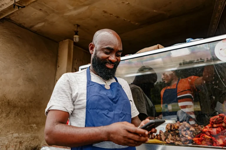 Shopkeeper in an apron checking messages on his phone
