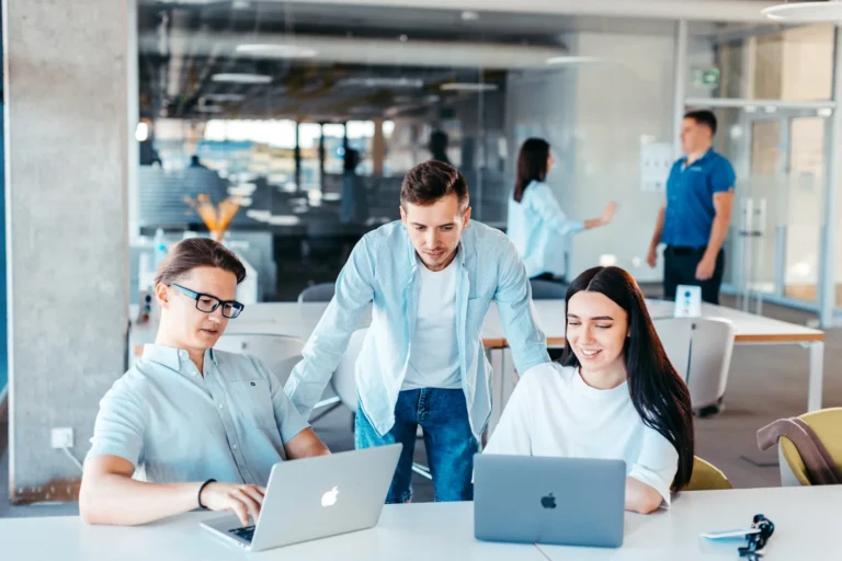 Marketing team collaborating around a laptop in an office