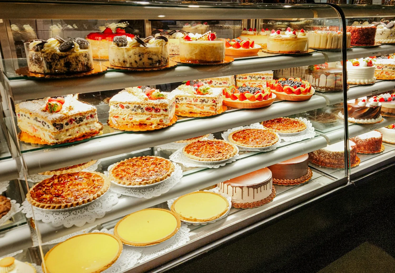 Glass bakery display case filled with cakes and tarts