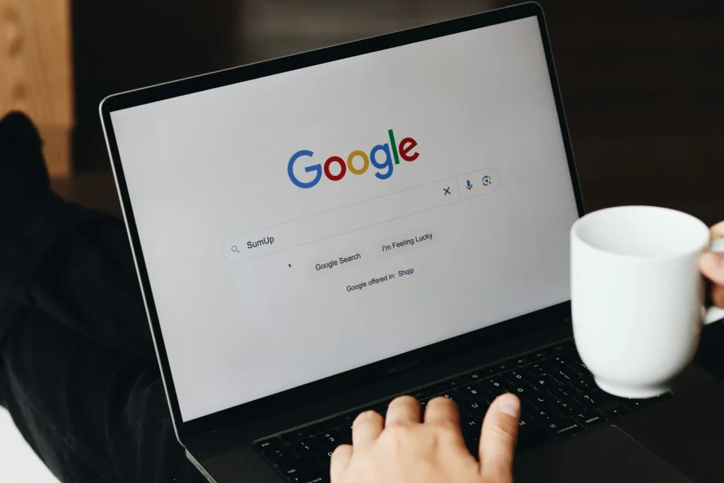 Laptop on a cafe table showing the Google search homepage