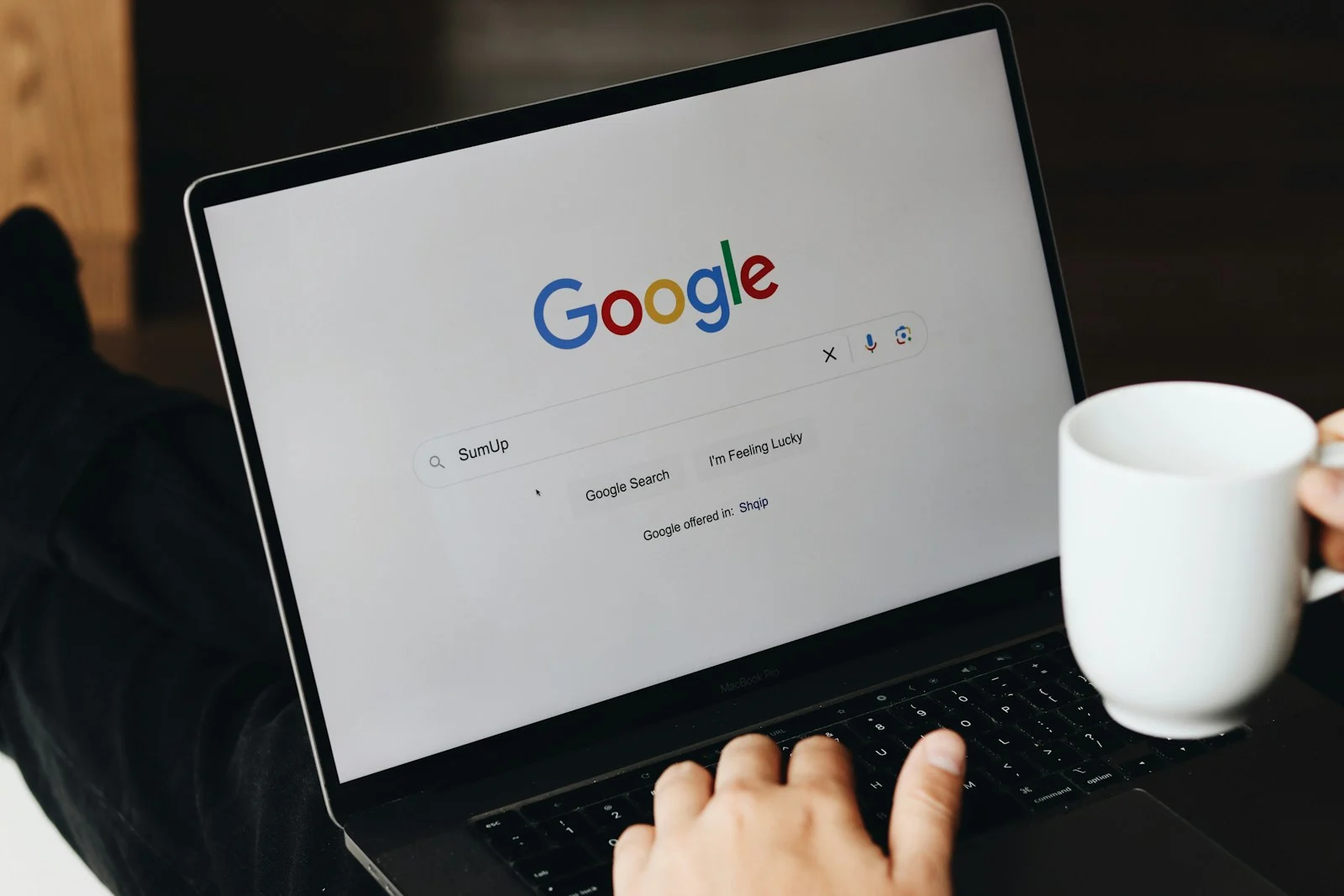 Laptop on a cafe table showing the Google search homepage