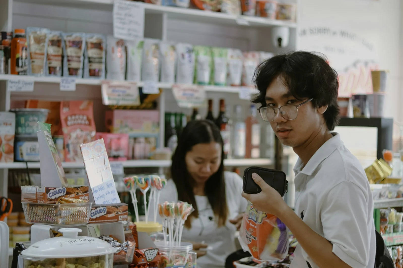Two customers looking at a phone while browsing a small retail shop