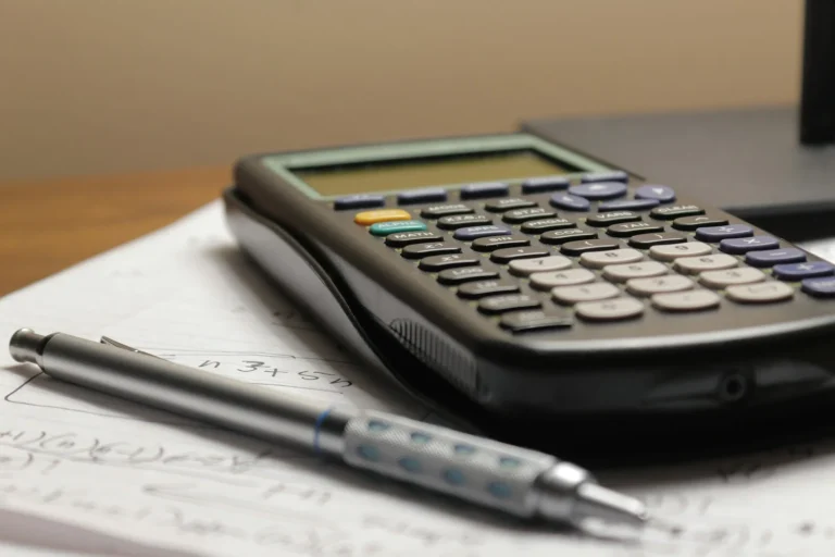 Calculator and pen resting on handwritten notes while planning a budget