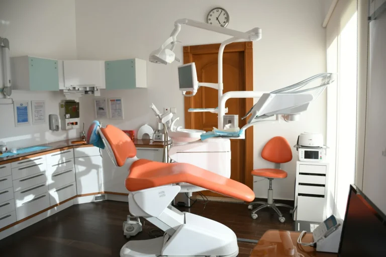 Empty dental clinic treatment room with an orange patient chair