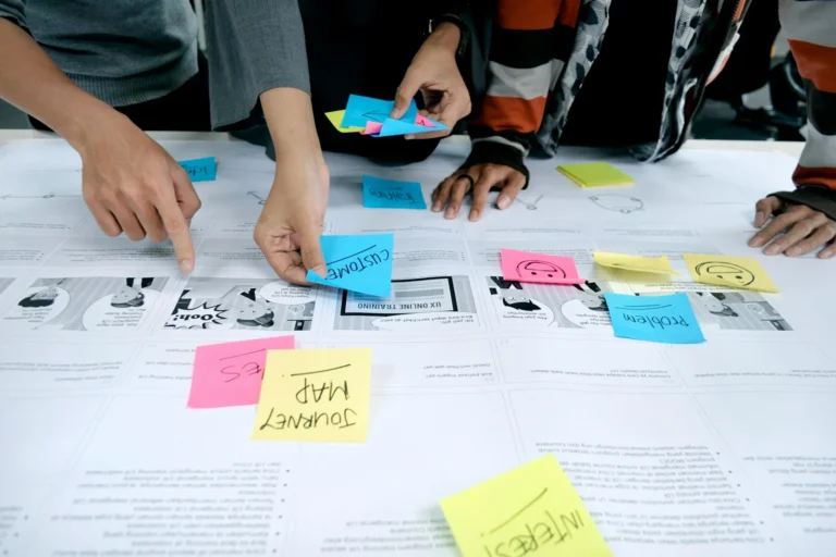 Team arranging sticky notes on a printed plan while mapping out content topics