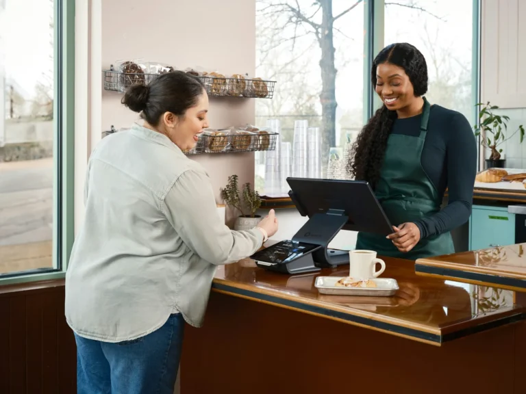 Customer paying at the counter of a small shop while the owner rings up the sale