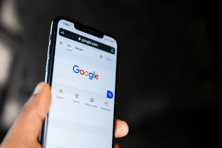 Hand holding a smartphone open on the Google search homepage