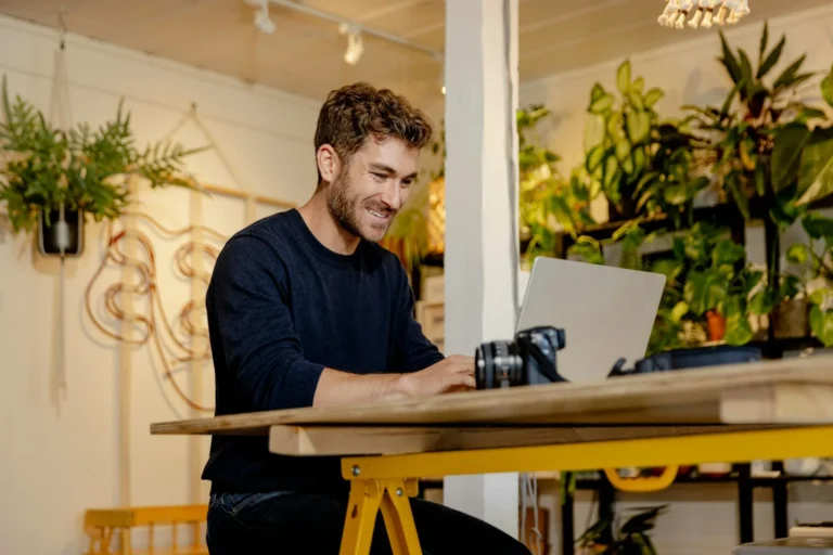 Business owner smiling while working on a laptop at a cafe table