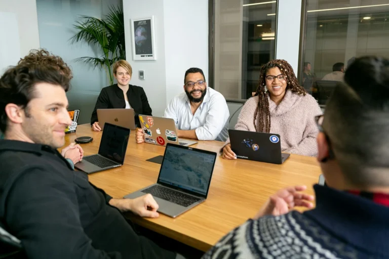 Agency team reviewing a client marketing plan on laptops around a meeting table