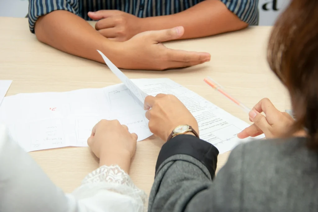 Two people going over printed documents together at a meeting table