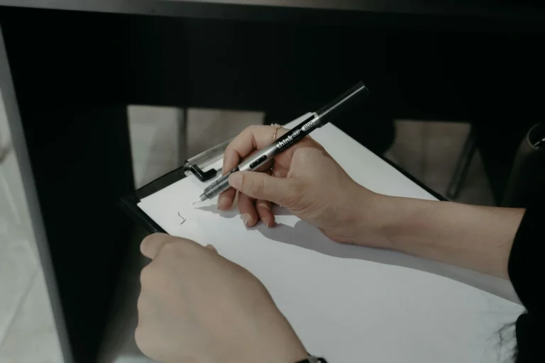 Hand writing a list of questions on a clipboard with a pen
