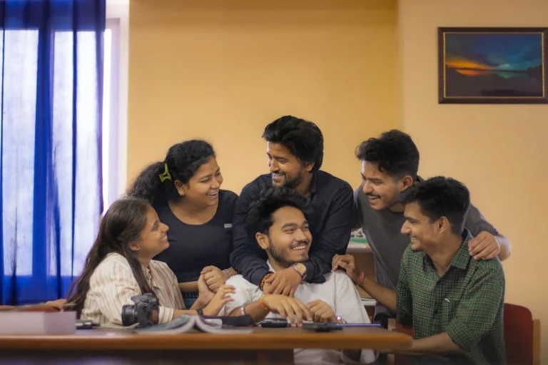 Small team of colleagues laughing together around an office table