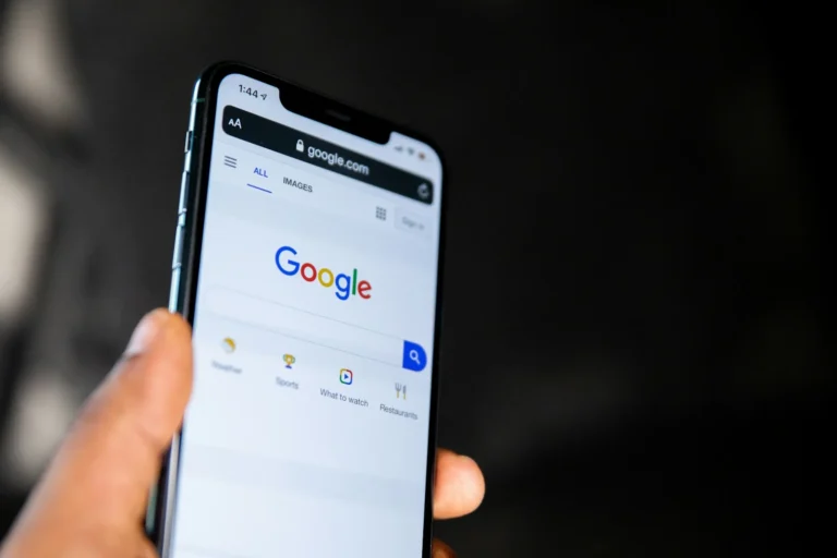 Hand holding a smartphone open on the Google search homepage