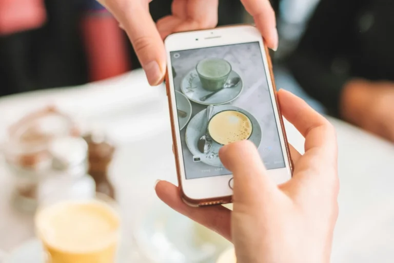 Person photographing two cups of tea on a cafe table with a smartphone