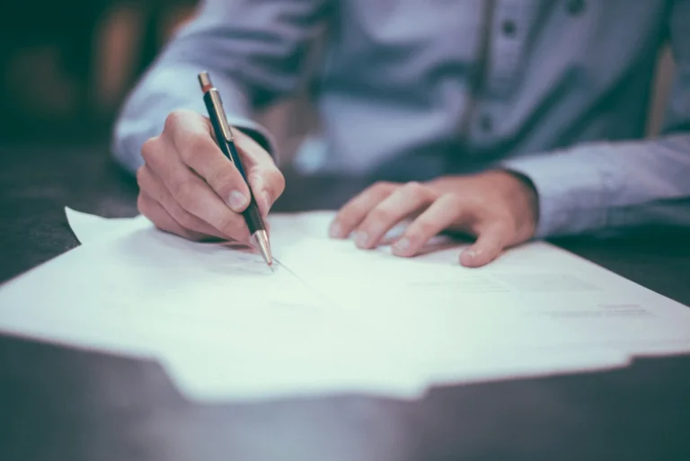 Close-up of a hand with a pen marking up a printed document