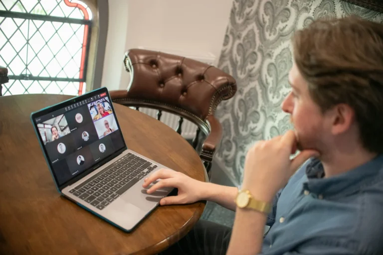 Man on a laptop video call with several colleagues on screen