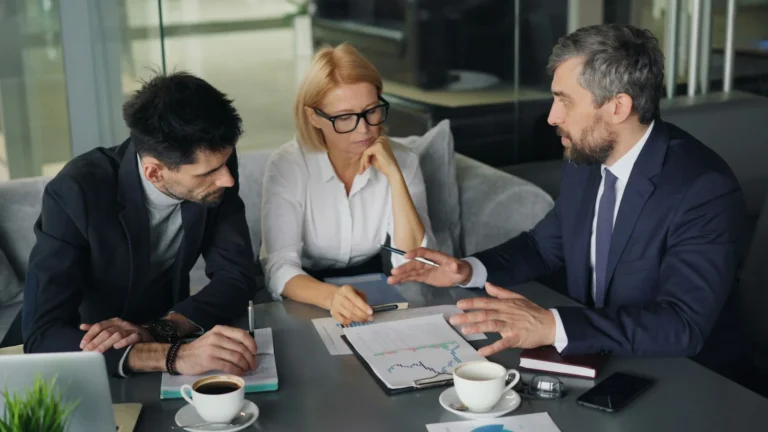 Business owner and two advisors reviewing documents at a meeting table