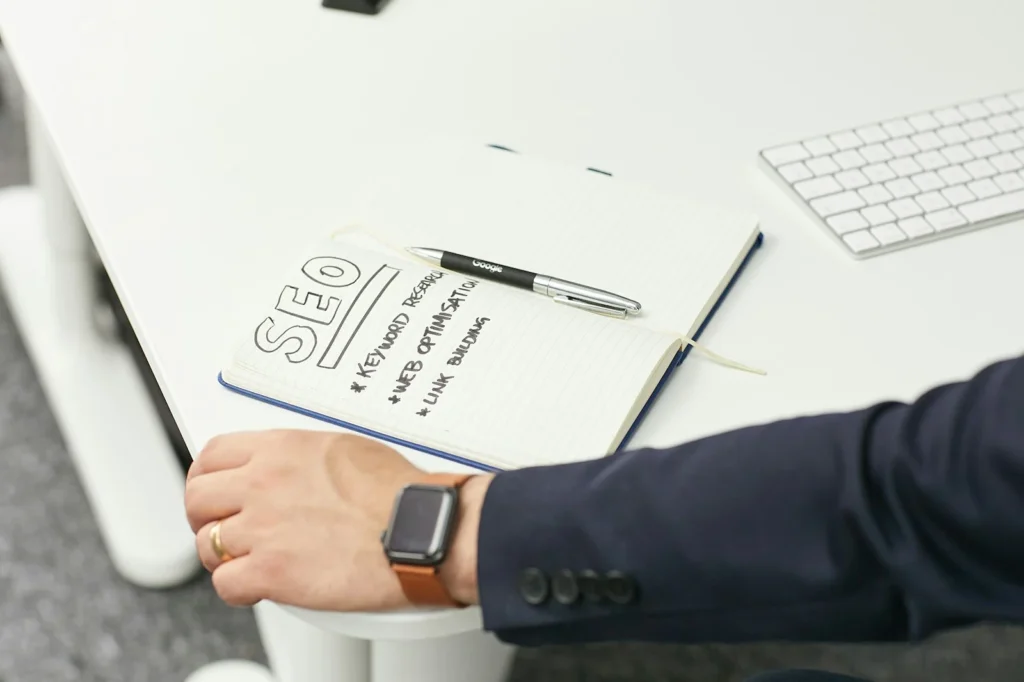 Hand resting on a notebook of SEO planning notes beside a keyboard