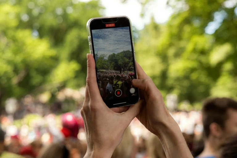 Hands holding a smartphone to record video outdoors