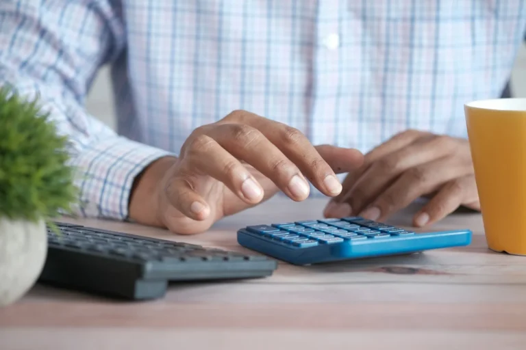Person working out a budget on a calculator at a desk
