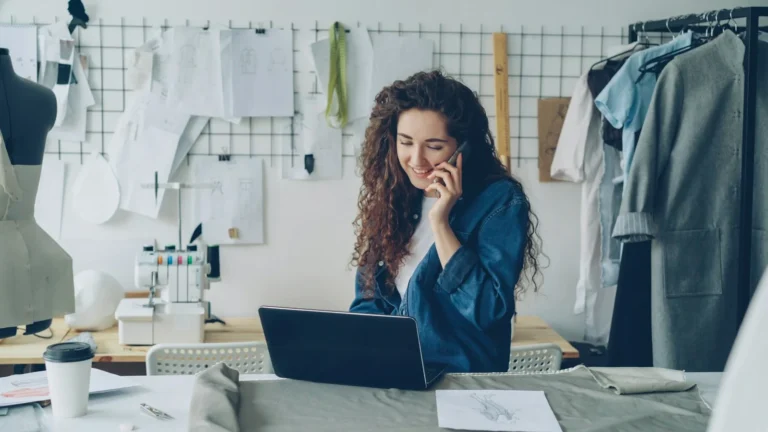 Small business owner on a phone call while working on a laptop in her studio