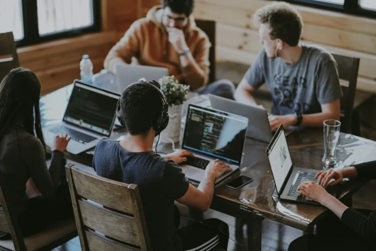 Small team answering messages on laptops around a shared table