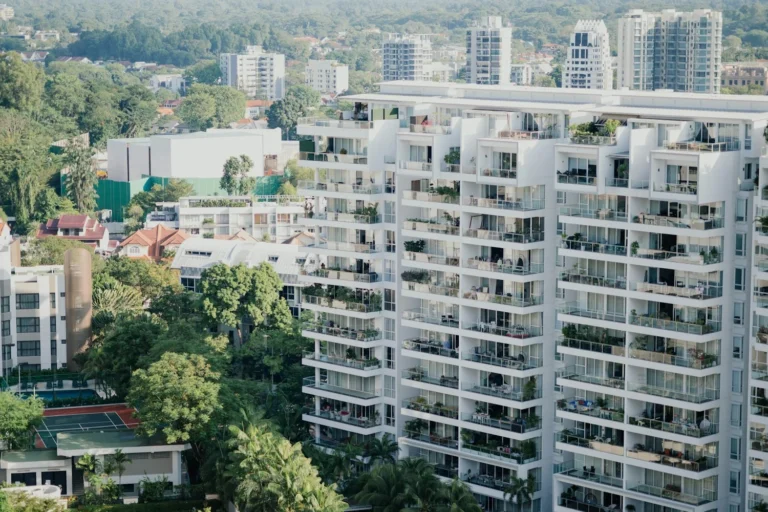 White apartment towers with balconies surrounded by trees