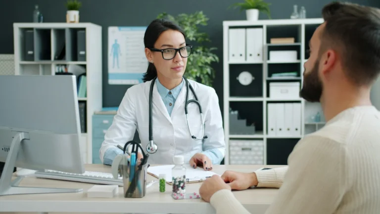 Doctor in a white coat consulting with a patient across a clinic desk