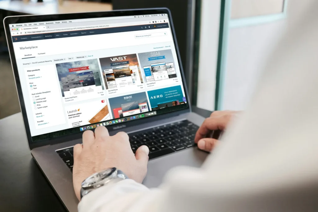 Hands typing on a laptop showing a website theme marketplace, one line item in website development cost in India