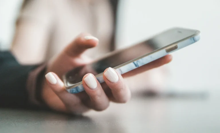 Hand holding a smartphone to manage which ads appear in WhatsApp Status