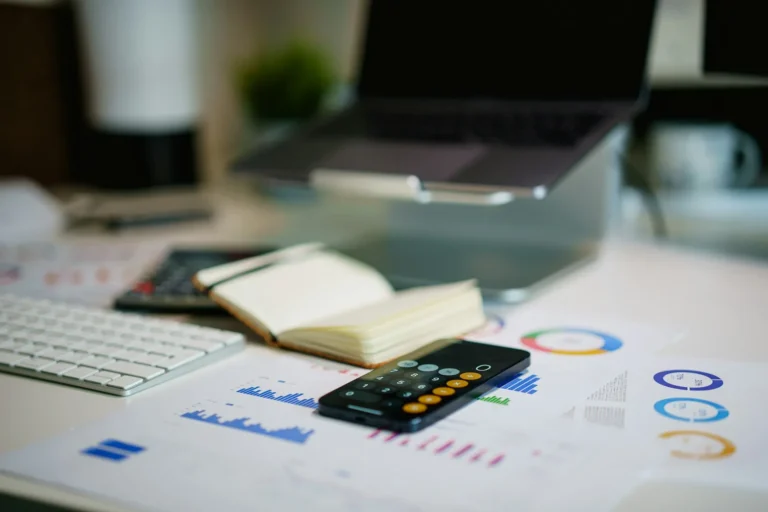 Desk with a phone, calculator and printed charts for planning an ad budget