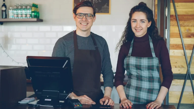 Two cafe staff smiling behind a counter in a restaurant