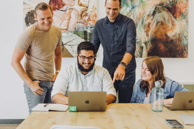 Team reviewing monthly review numbers around a laptop