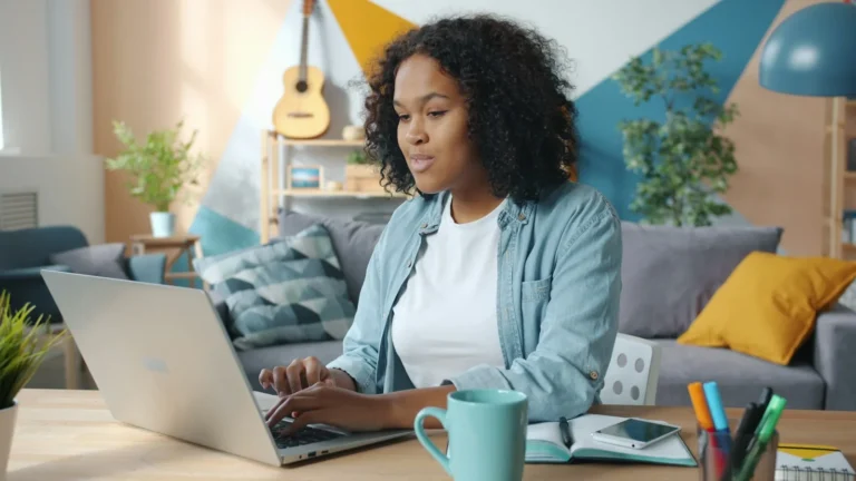 Woman working on a laptop at a home desk, writing a newsletter