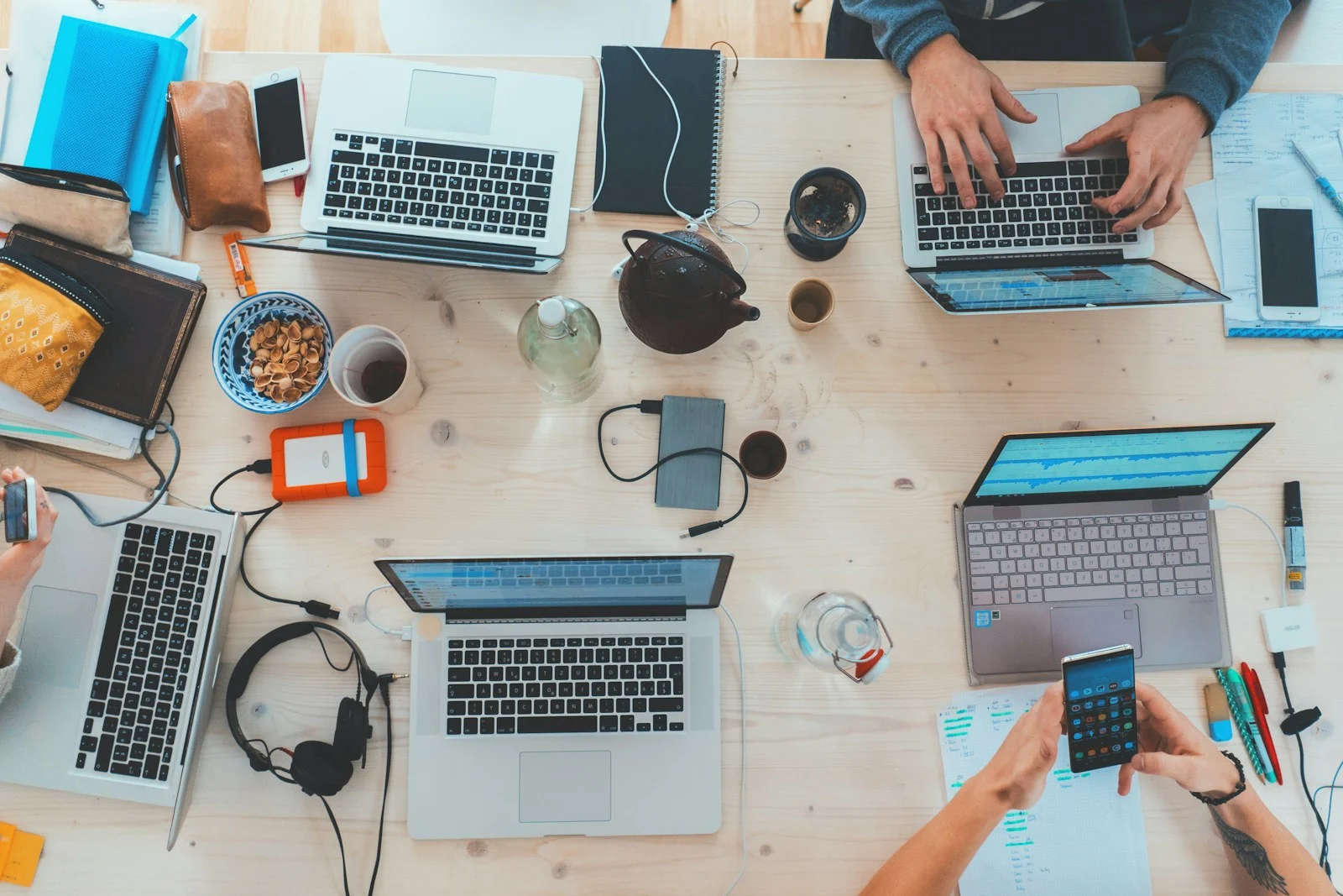 Digital marketing services planned around a table of laptops, notebooks and phones